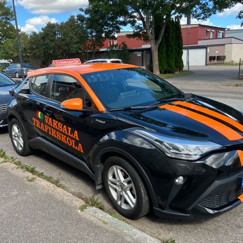 En svart och orange bil på bilskolan.